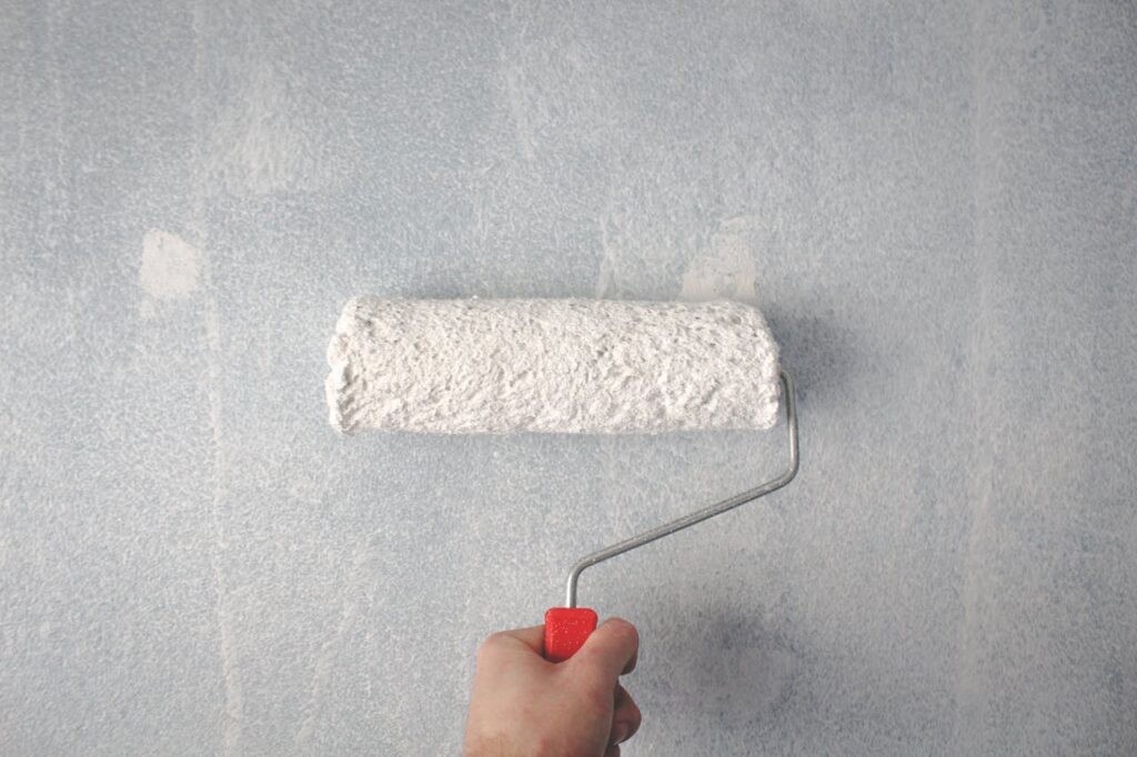 Person Holding Paint Roller On Wall